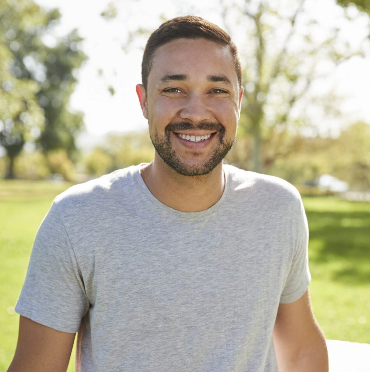 Outdoor Head And Shoulders Portrait Of Smiling Man In Park